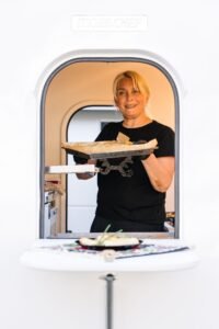 Cuisinière ZVRK servant une pita à la fenêtre du foodtruck à Bruxelles